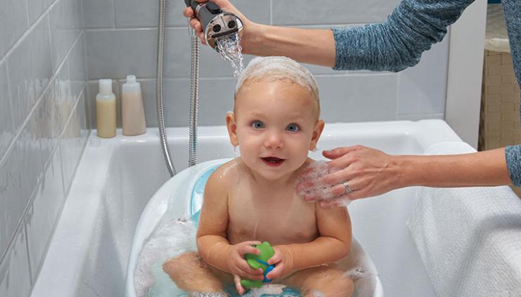 Mother washing baby in bathtub