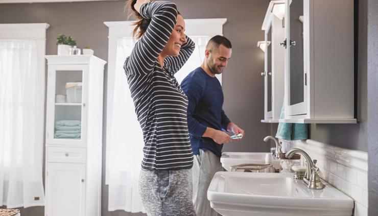 Man and woman in small bathroom getting ready for the day