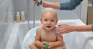 Mother washing baby in bathtub