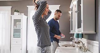 Man and woman in small bathroom getting ready for the day